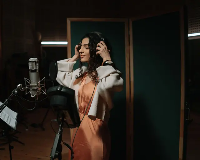 Singer with headphones recording in a studio booth