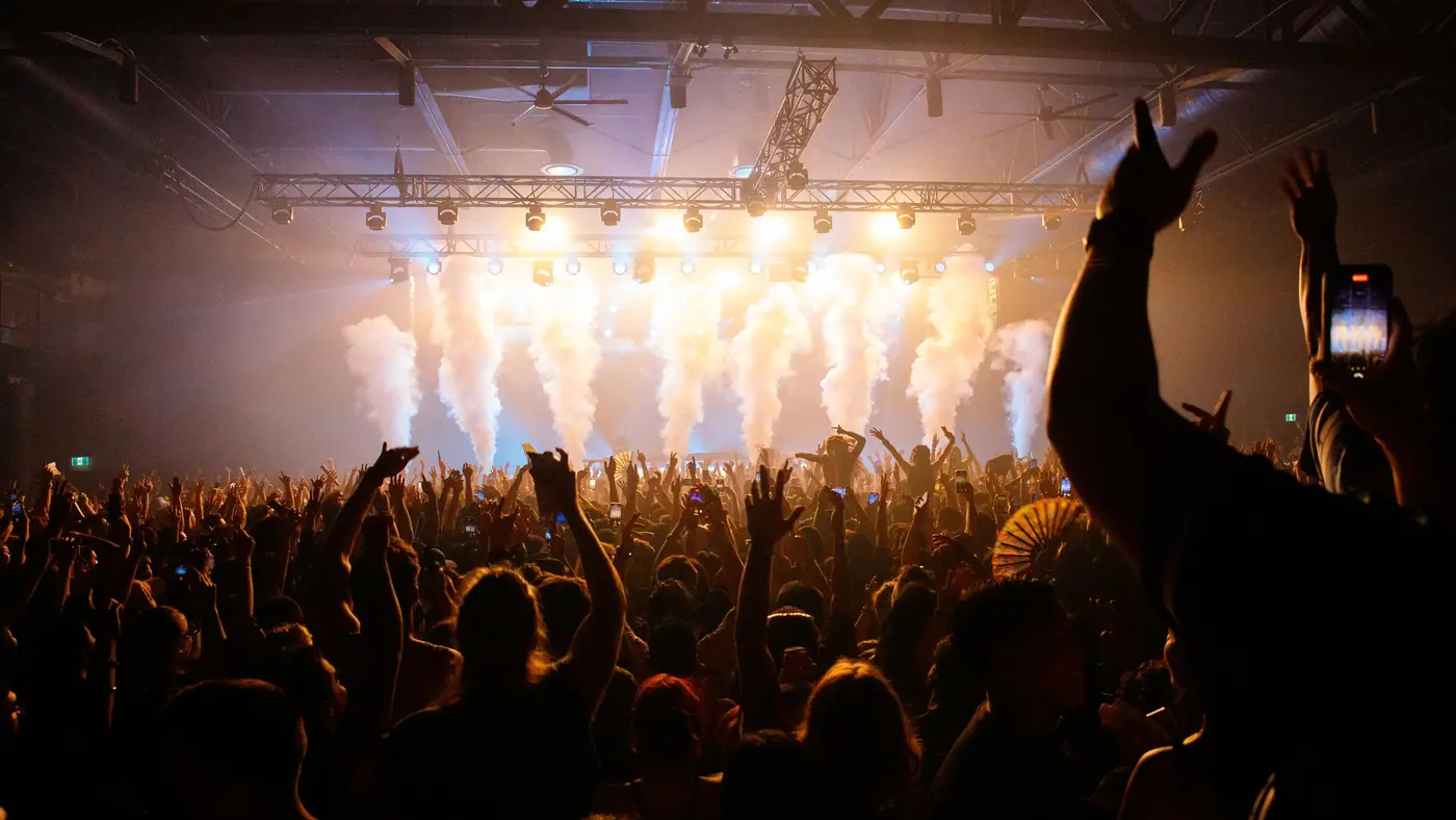 Concert crowd with raised hands under warm stage lights